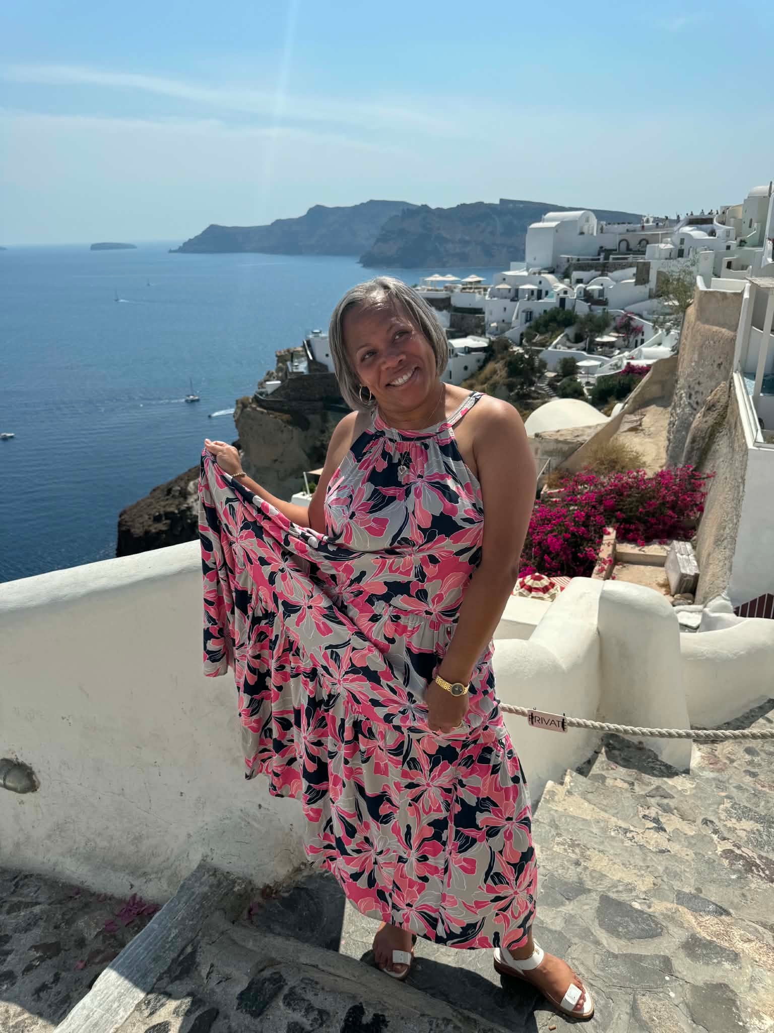Ms. Mia in a floral dress overlooking the Santorini caldera