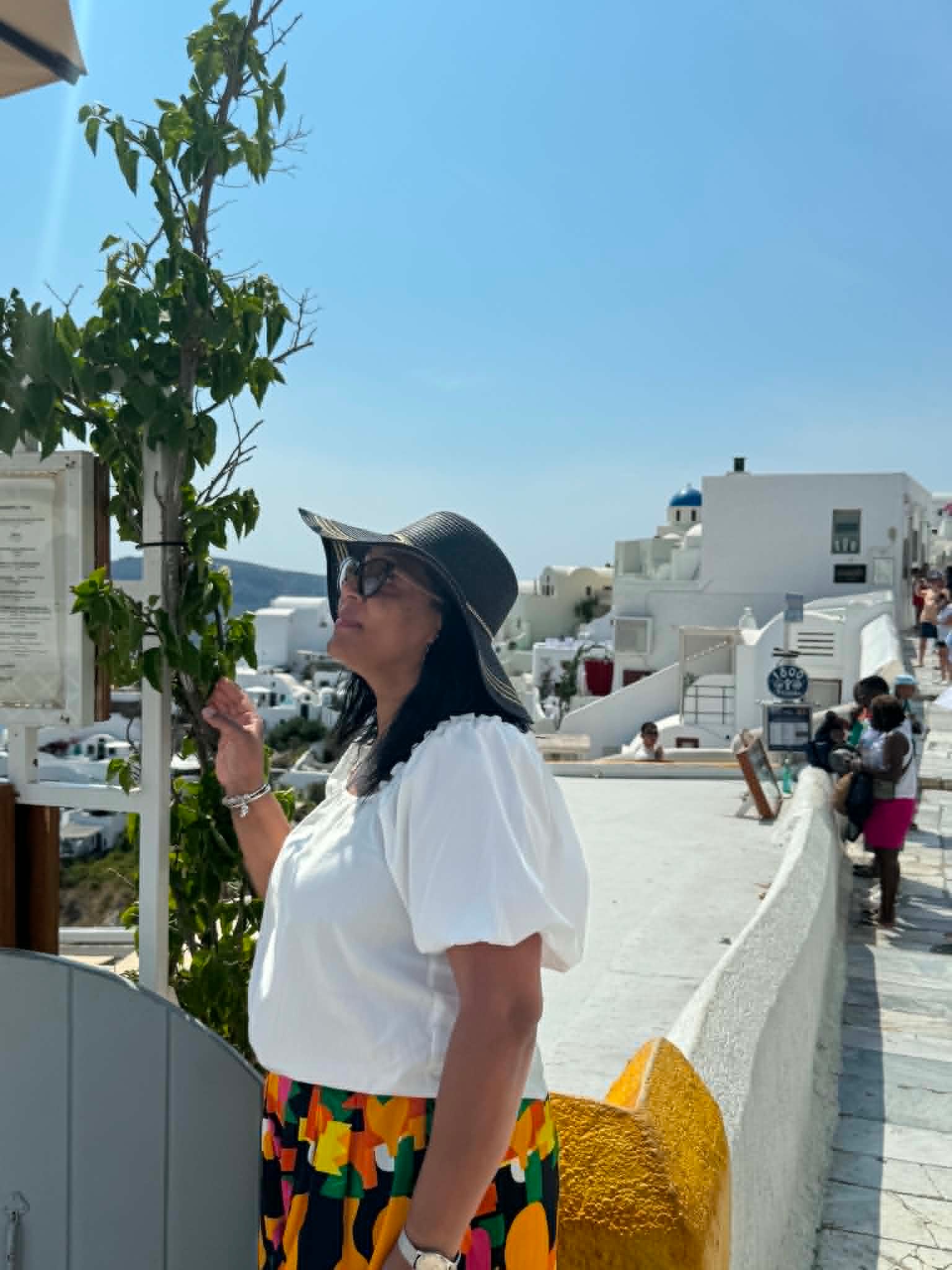 Woman in hat and colorful skirt in Santorini