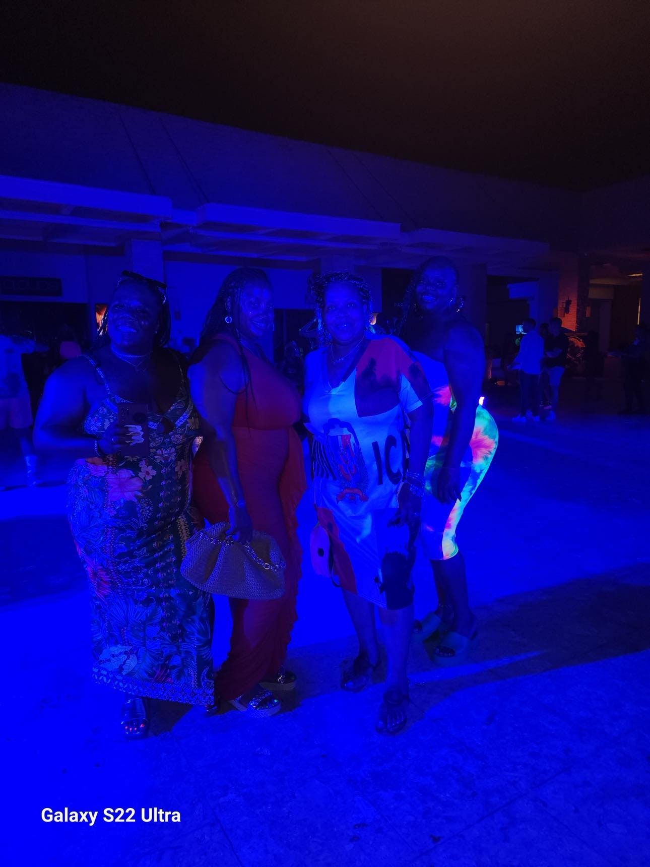 Group of friends glowing under blue blacklight at a beach party