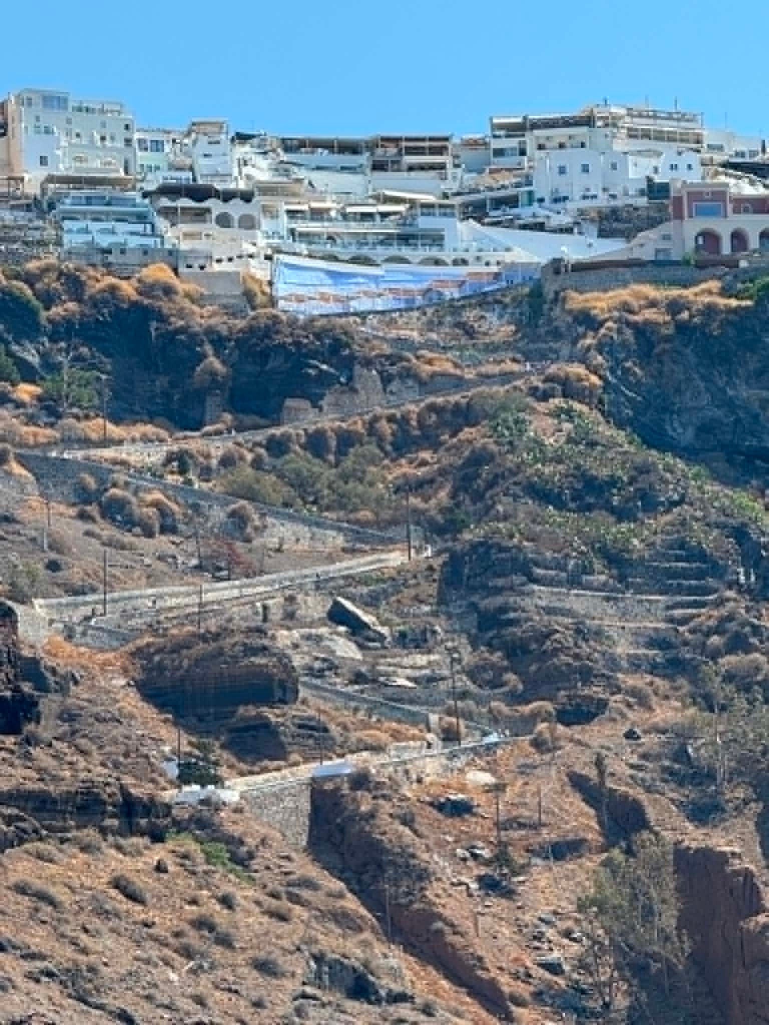 Scenic view of Santorini hillside with white buildings and winding trail